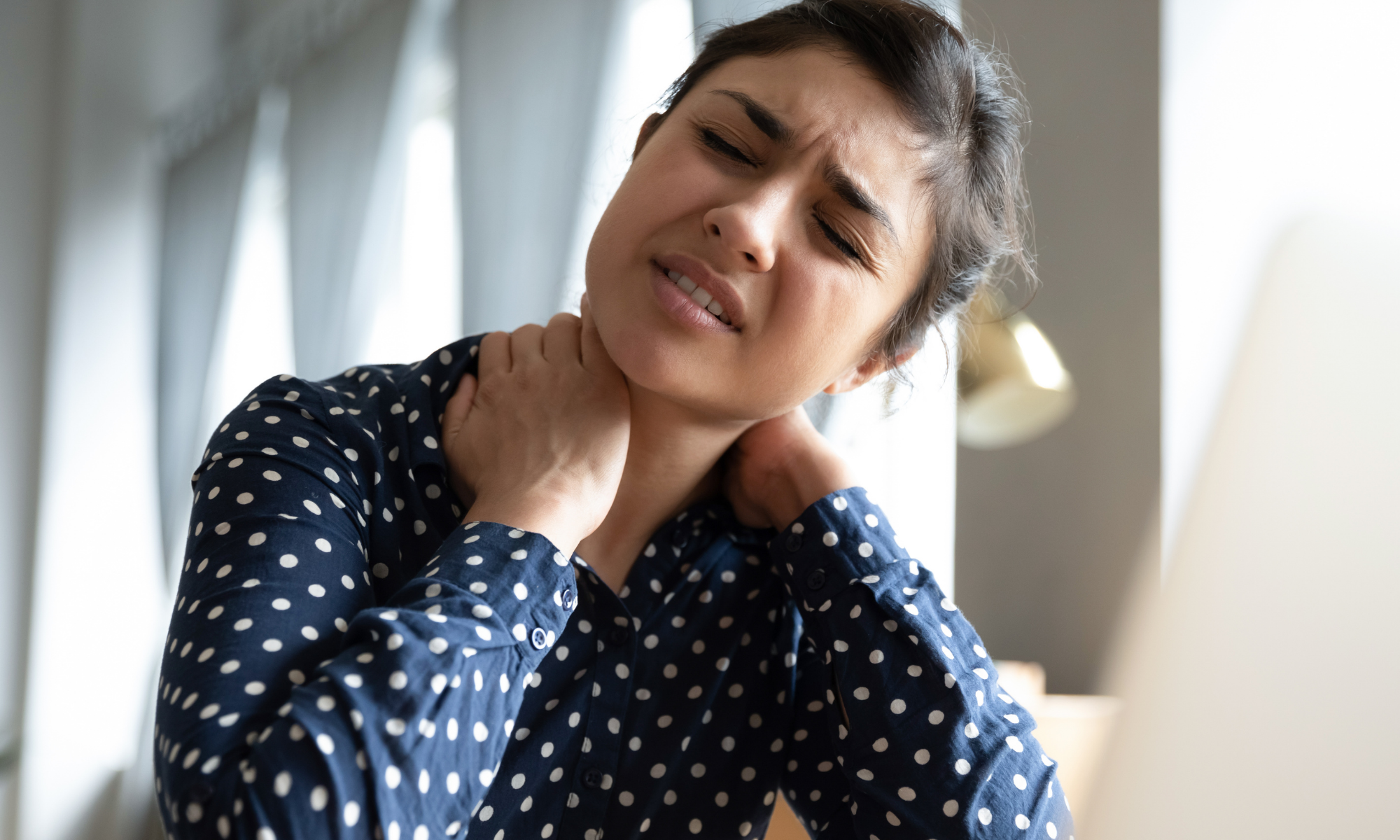Woman rubs neck in discomfort