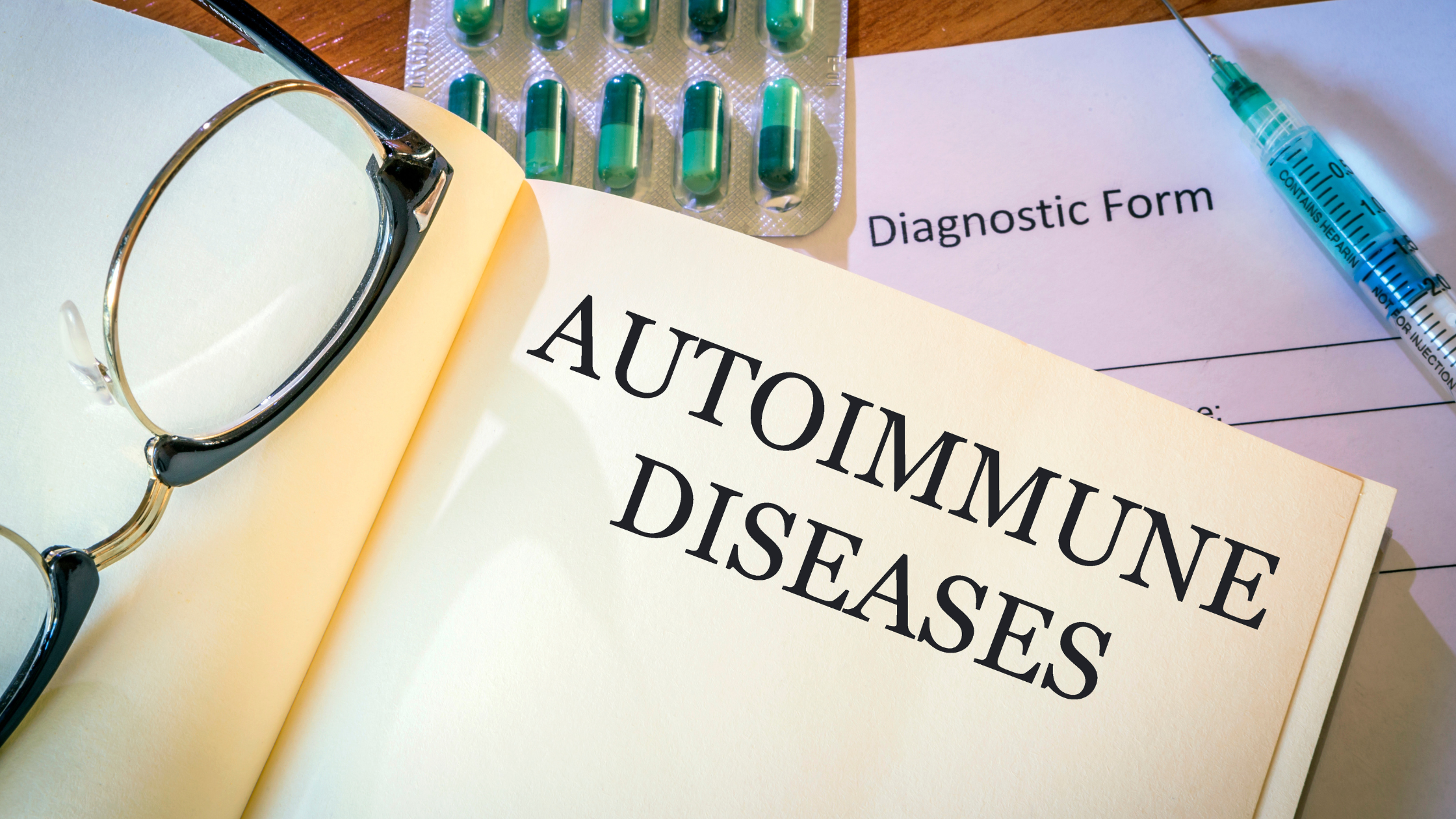 medical textbook open to "autoimmune diseases" with syringe, pills and a diagnostic form