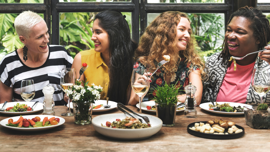 Group of women laughing and enjoying a meal together