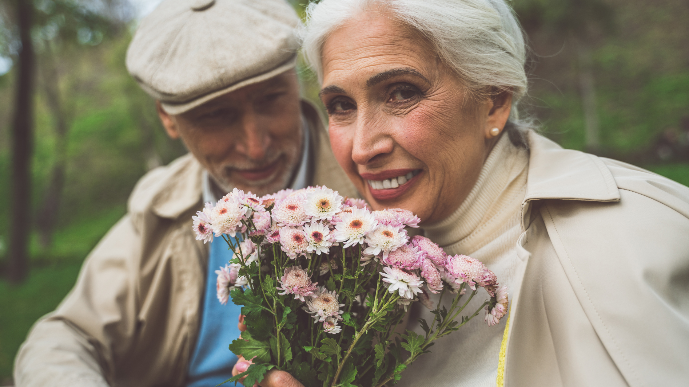 senior man smiling at senior woman with a bouquet of flowers