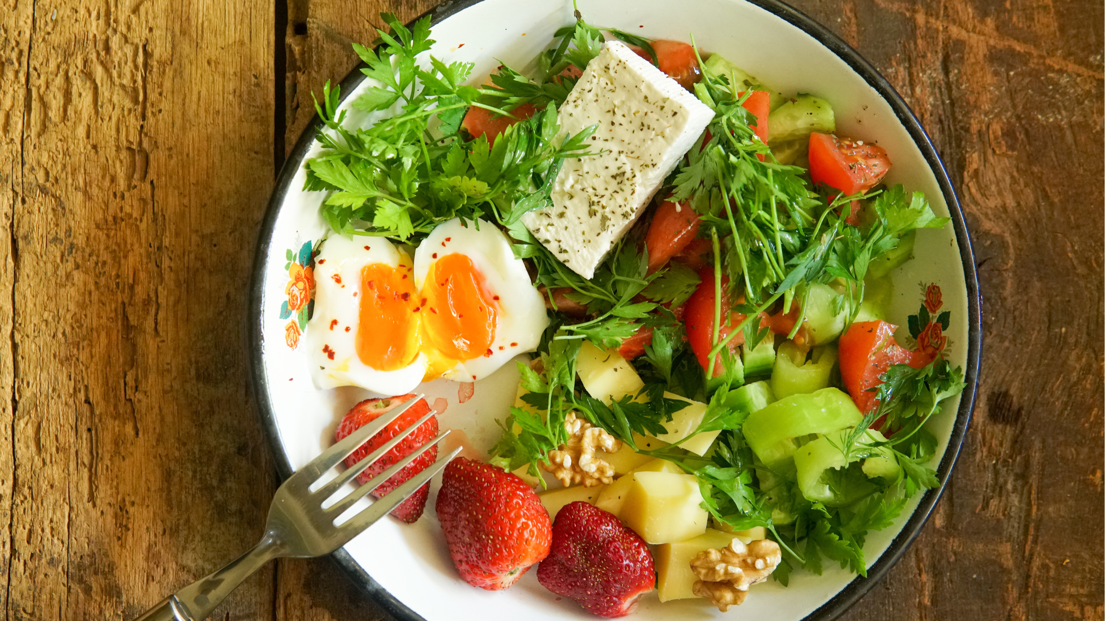 plate of fresh salad with some tofu, eggs, and berries