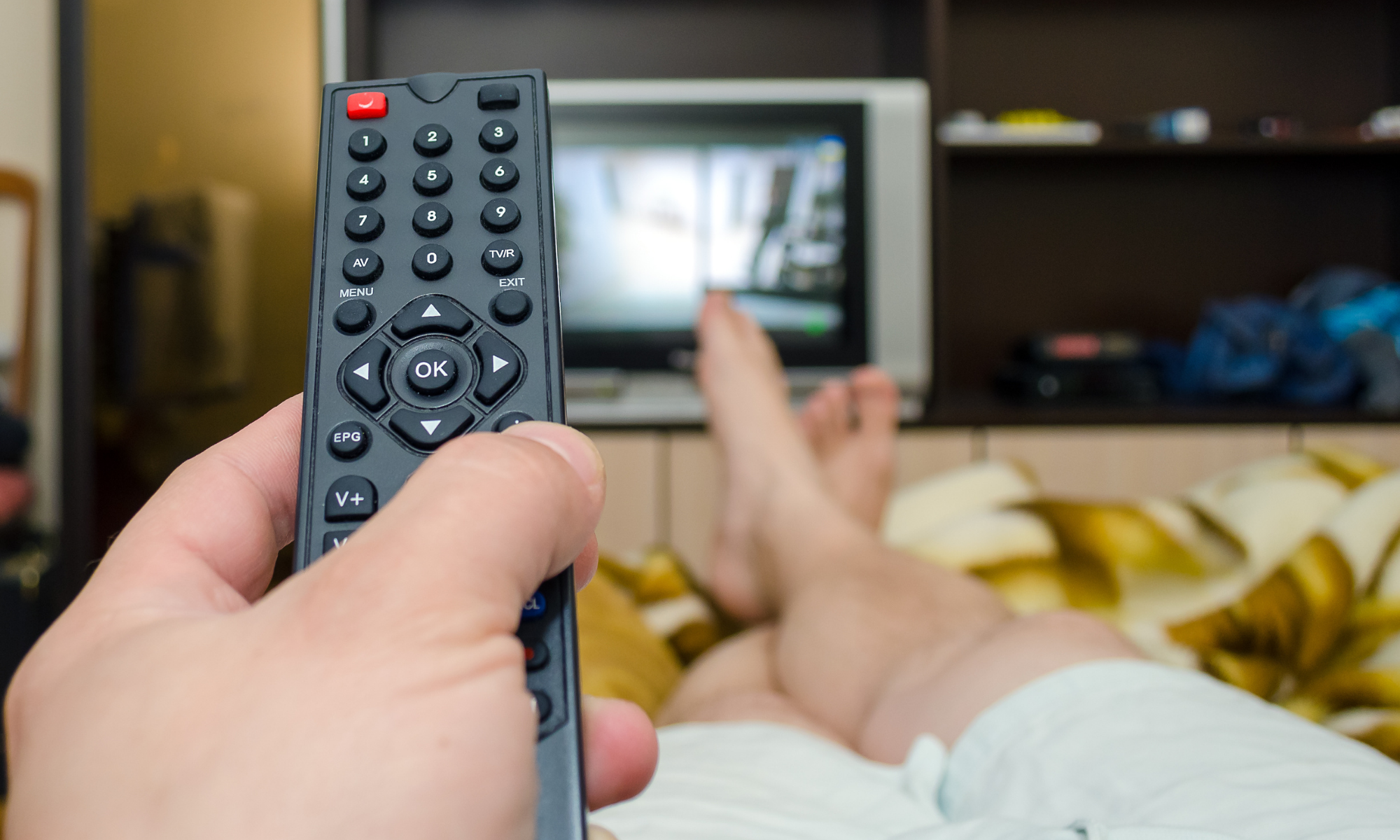 First person view from person holding a remote and channel-surfing in bed; Dieting alone without physical activity is unlikely to yield the desired results
