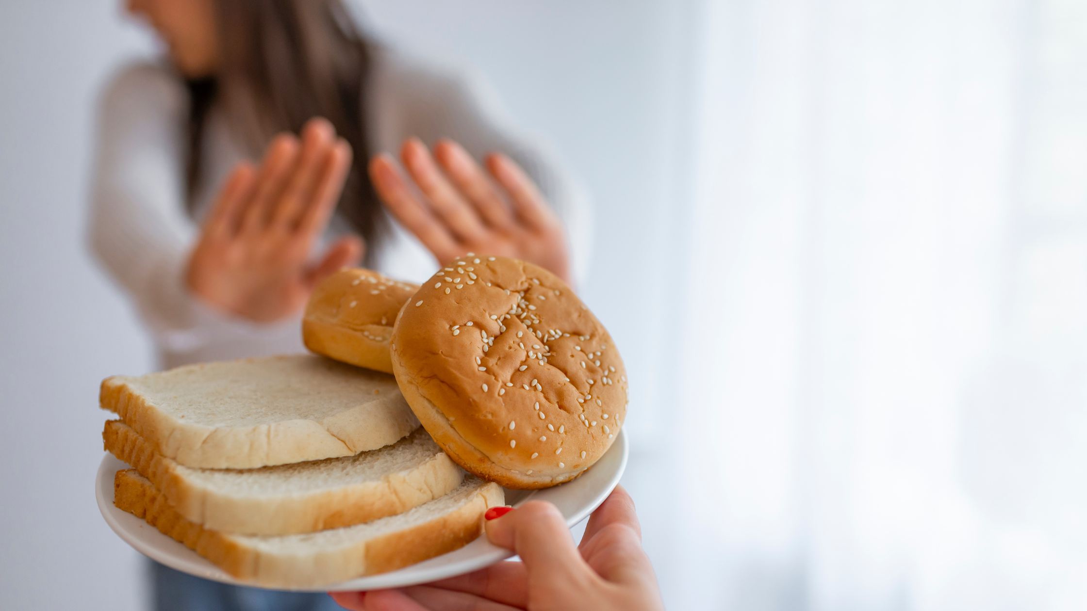 someone holds out their hands to decline a plate of bread and donuts