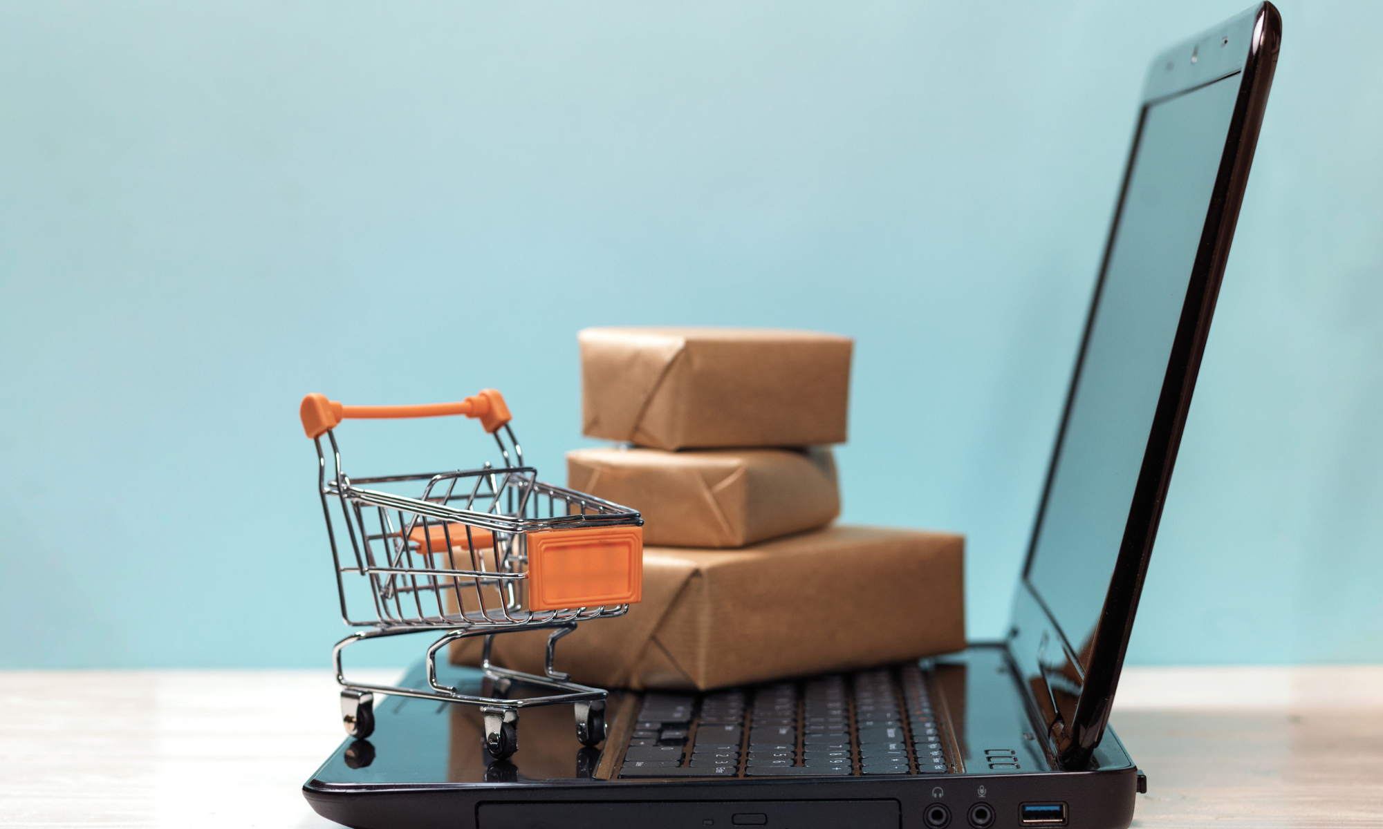 A tiny shopping cart and a package arranged on a laptop keyboard