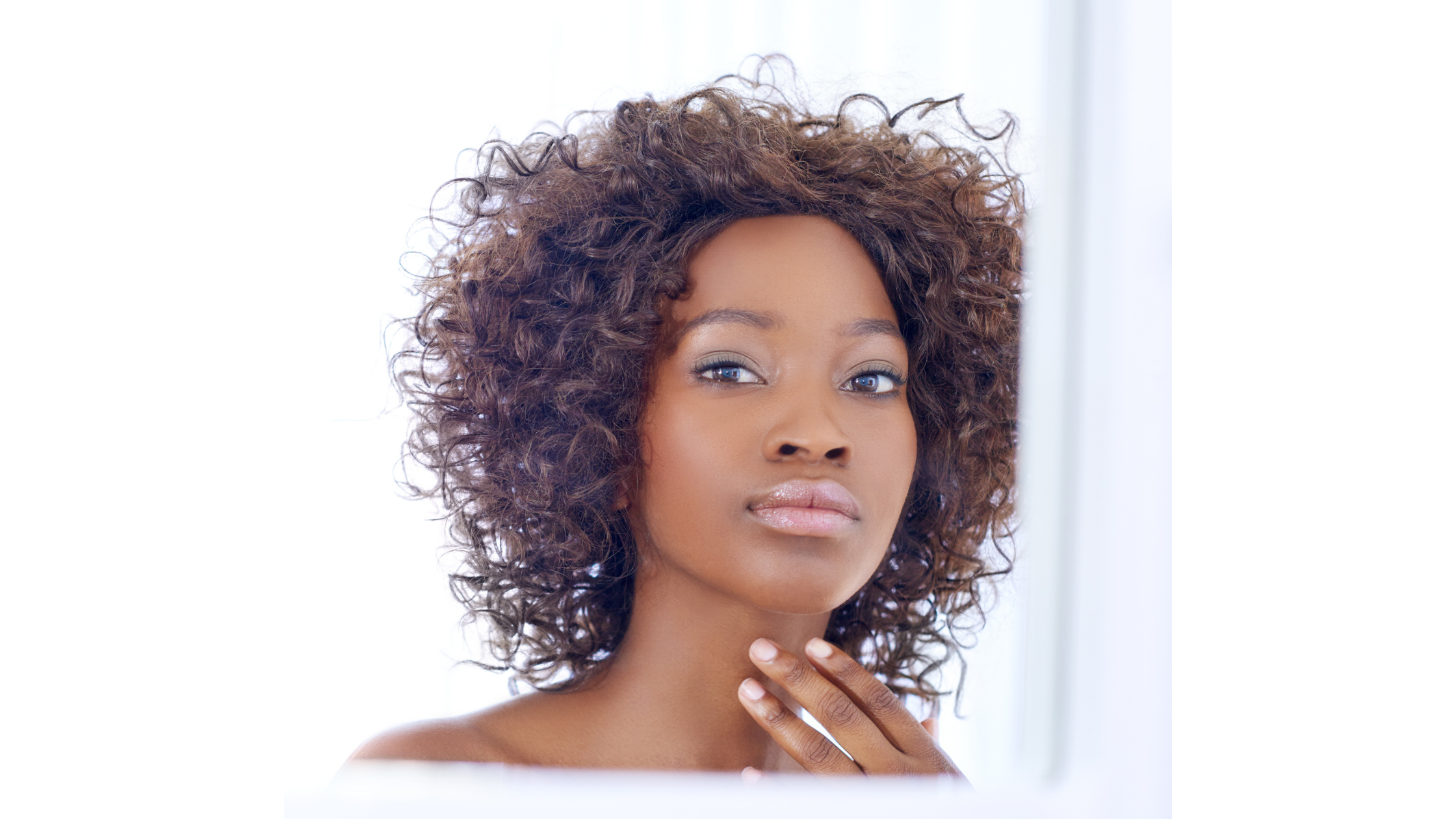 Young woman looking in the mirror and touching her neck