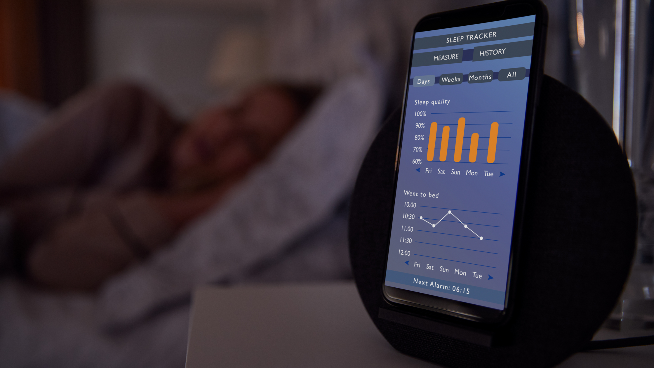 phone showing a sleep tracker open on a nightstand beside a sleeping person
