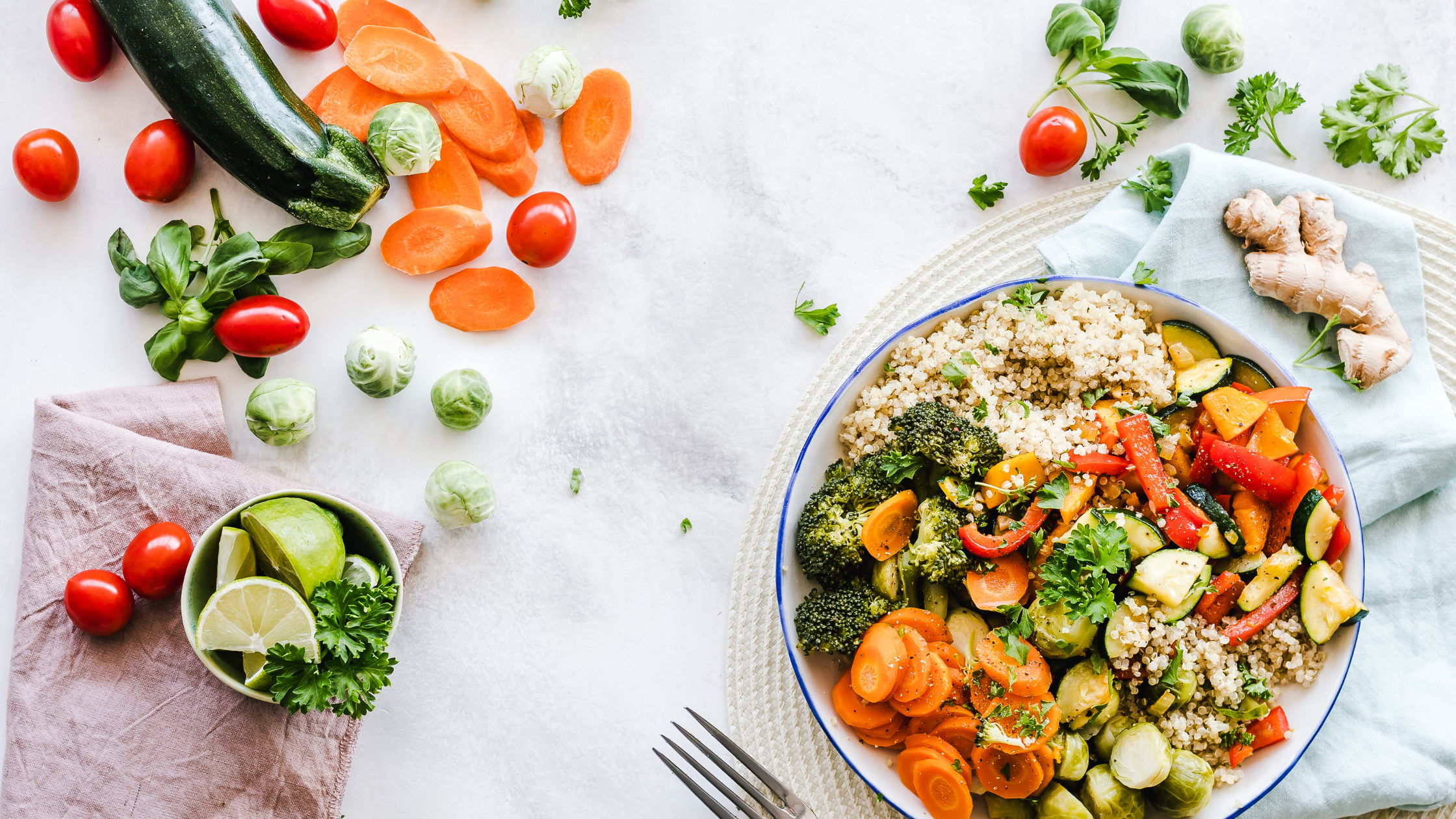 greens and grains bowl on a tabletop surrounded by raw veggies