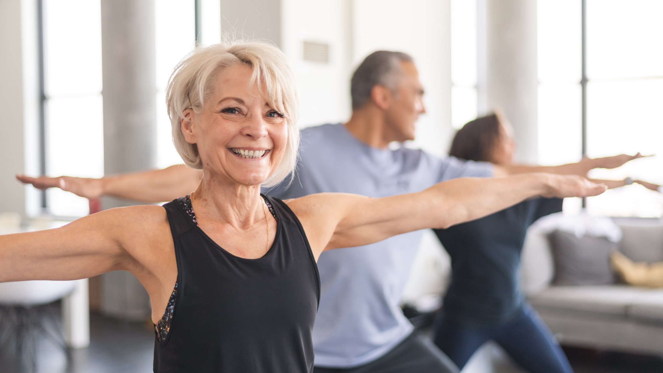 Happy older couple at the gym, towels over shoulder, woman holding yoga mat