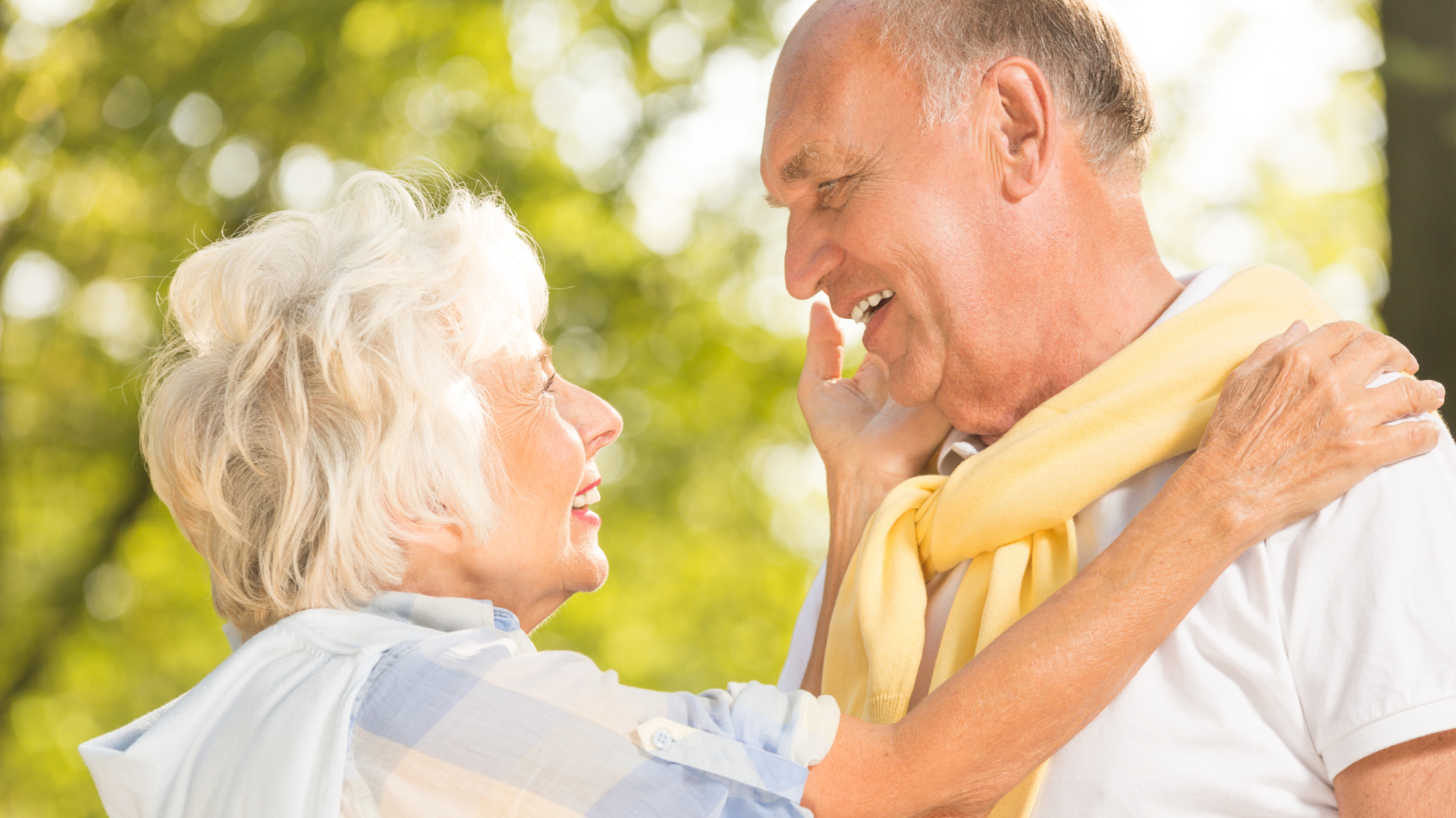 senior woman caressing senior man's cheek, both smile