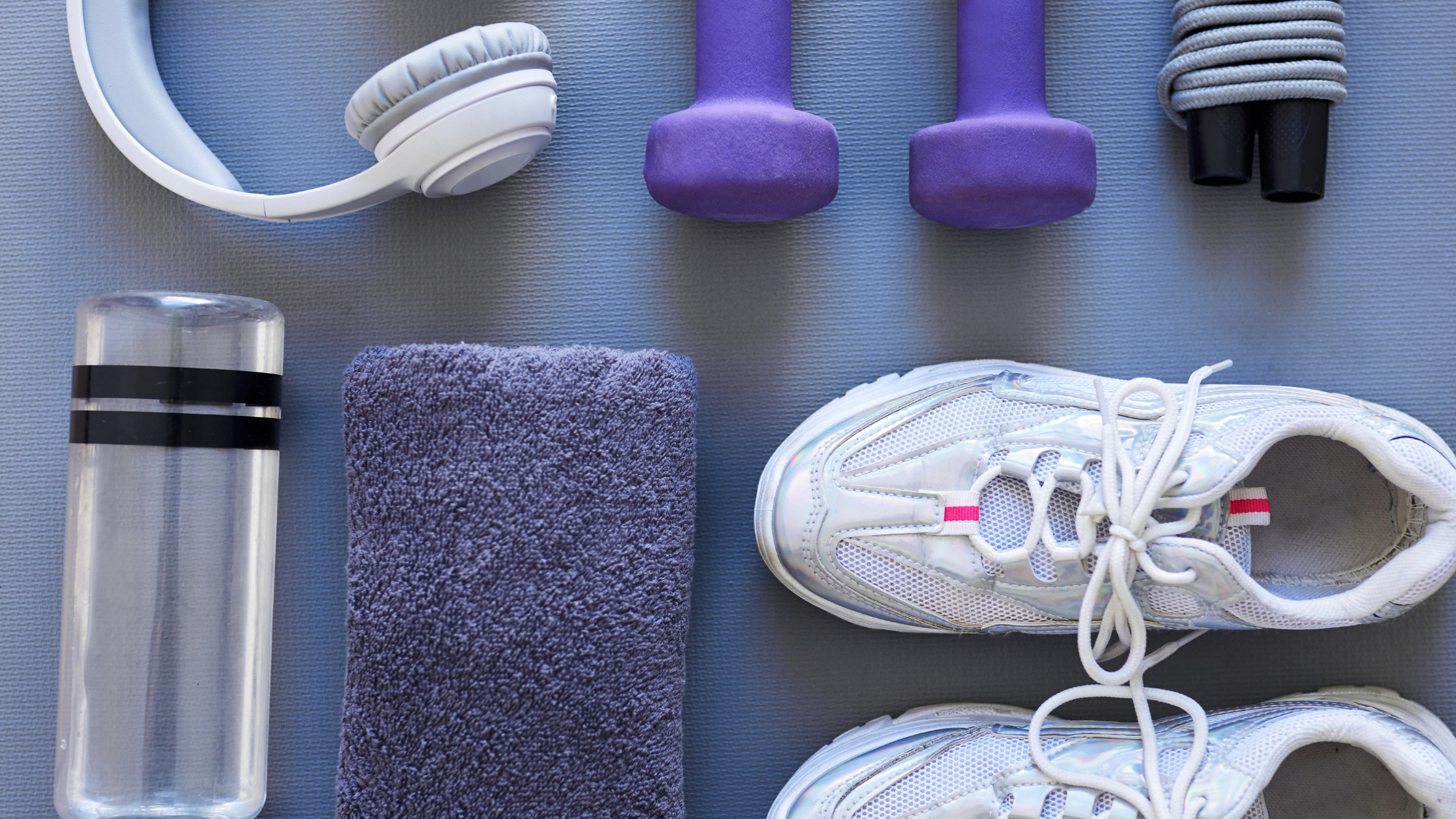 Various workout equipment, water bottle, free weights, headphones, jump rope, sneakers