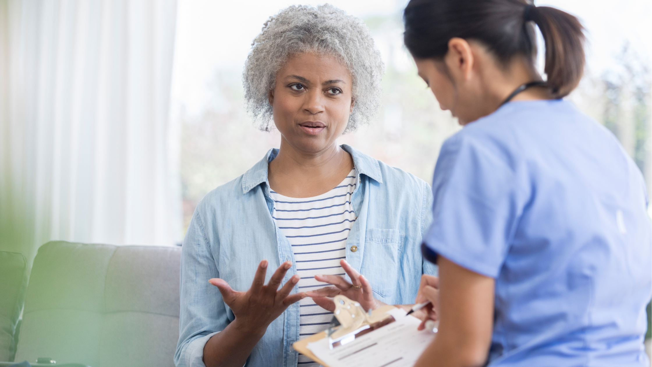 nurse with a clipboard listens to her patient and takes notes