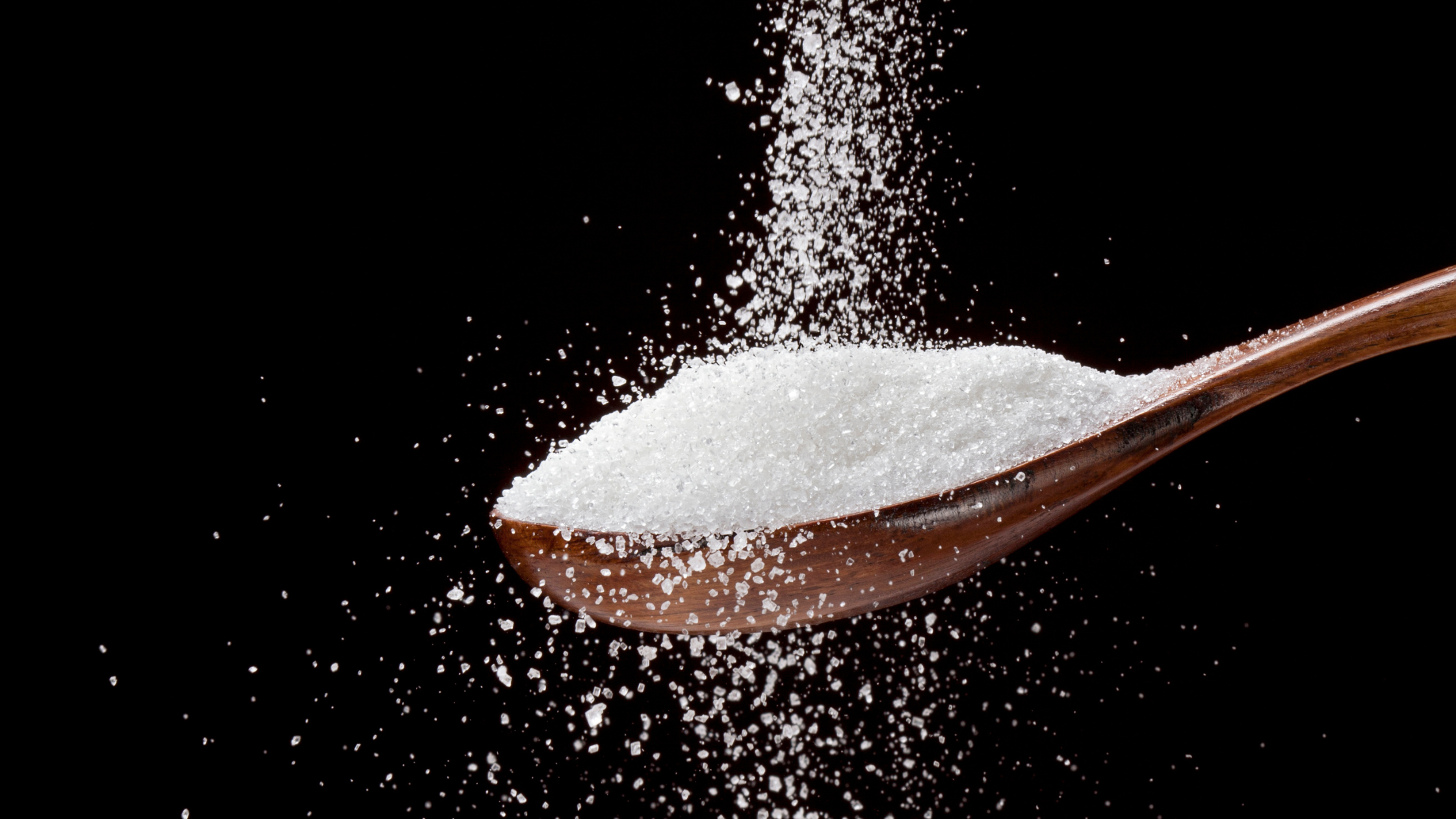 large wooden spoon overflowing with white sugar
