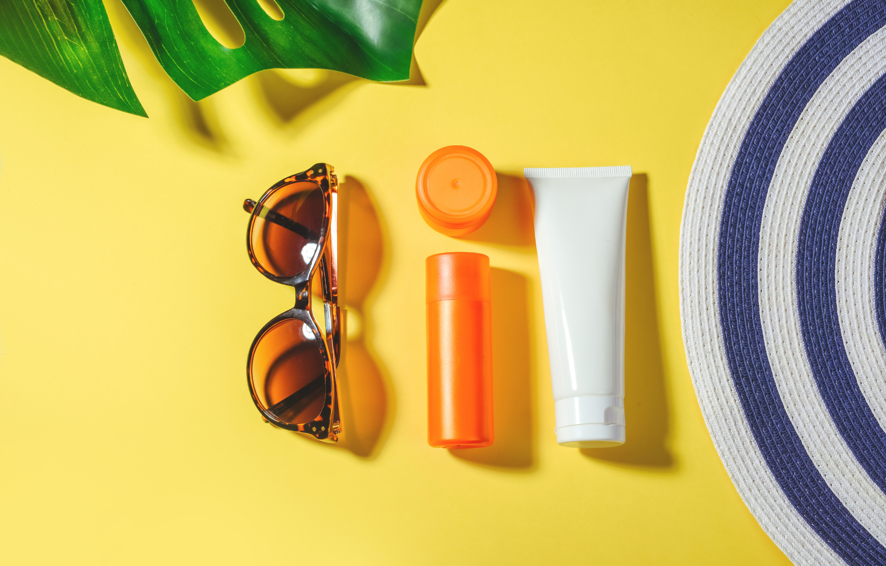 Sunglasses and sunscreen laid out on yellow table, preparing for the beach