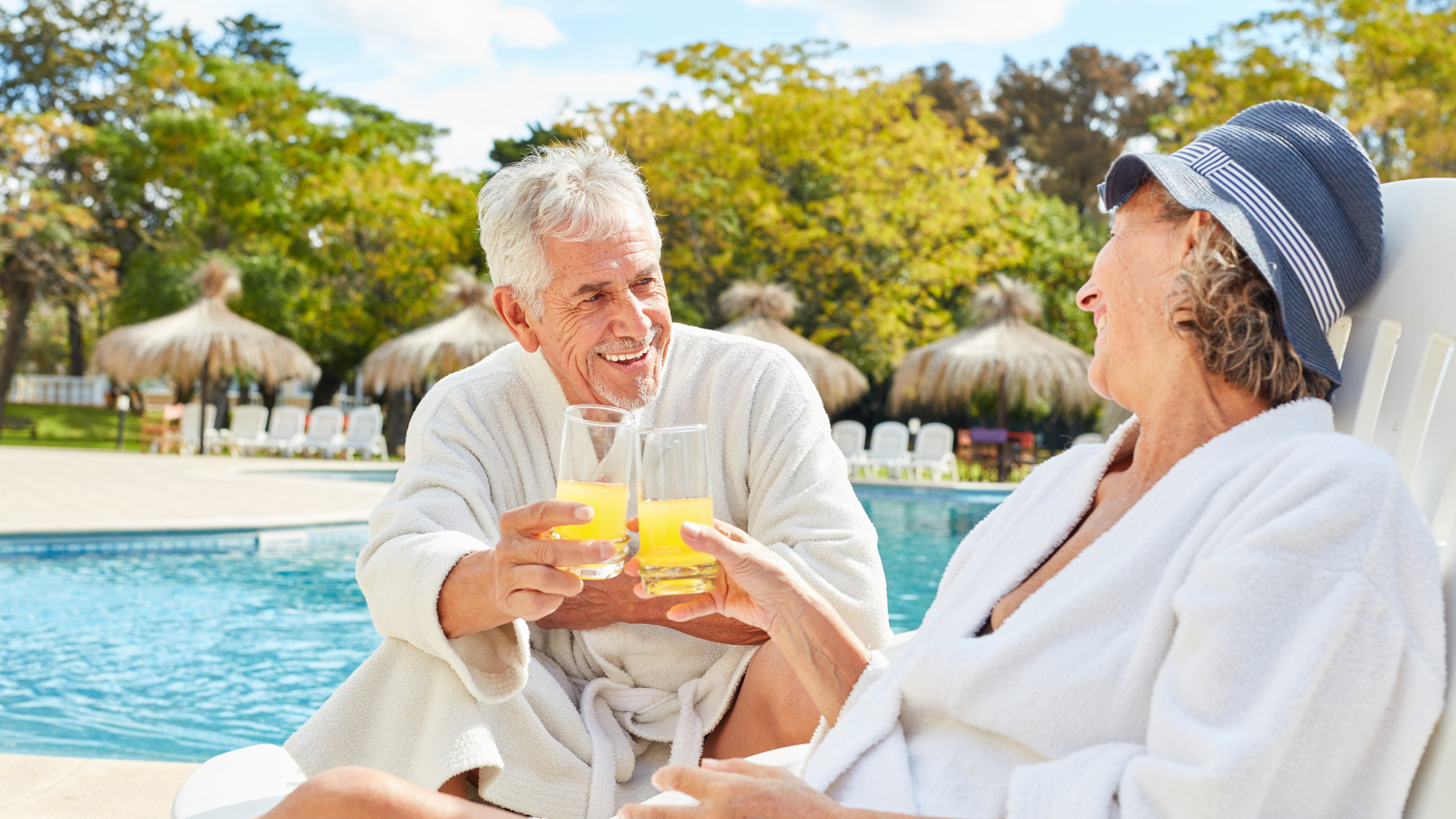 senior couple "cheers" each other beside a pool