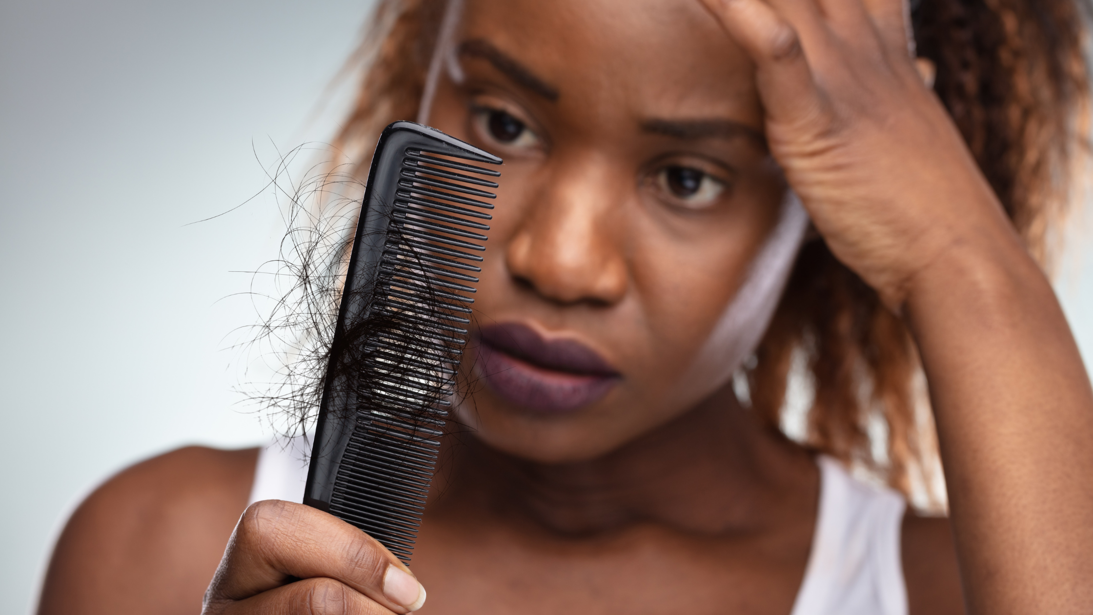 person looks at their comb, which is full of hair