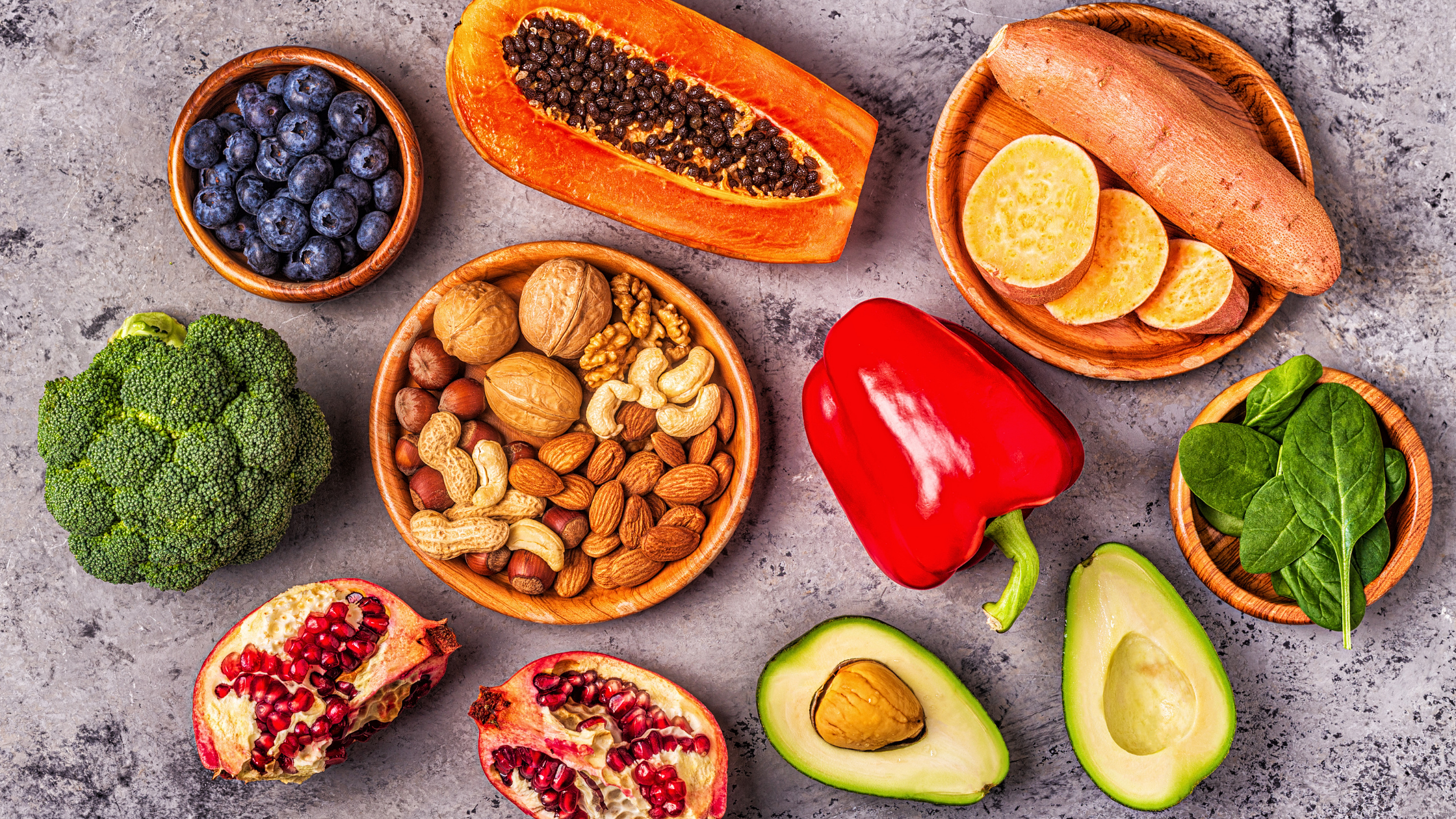 Various healthy-looking foods, avocados, broccoli, red pepper, blueberries, nuts