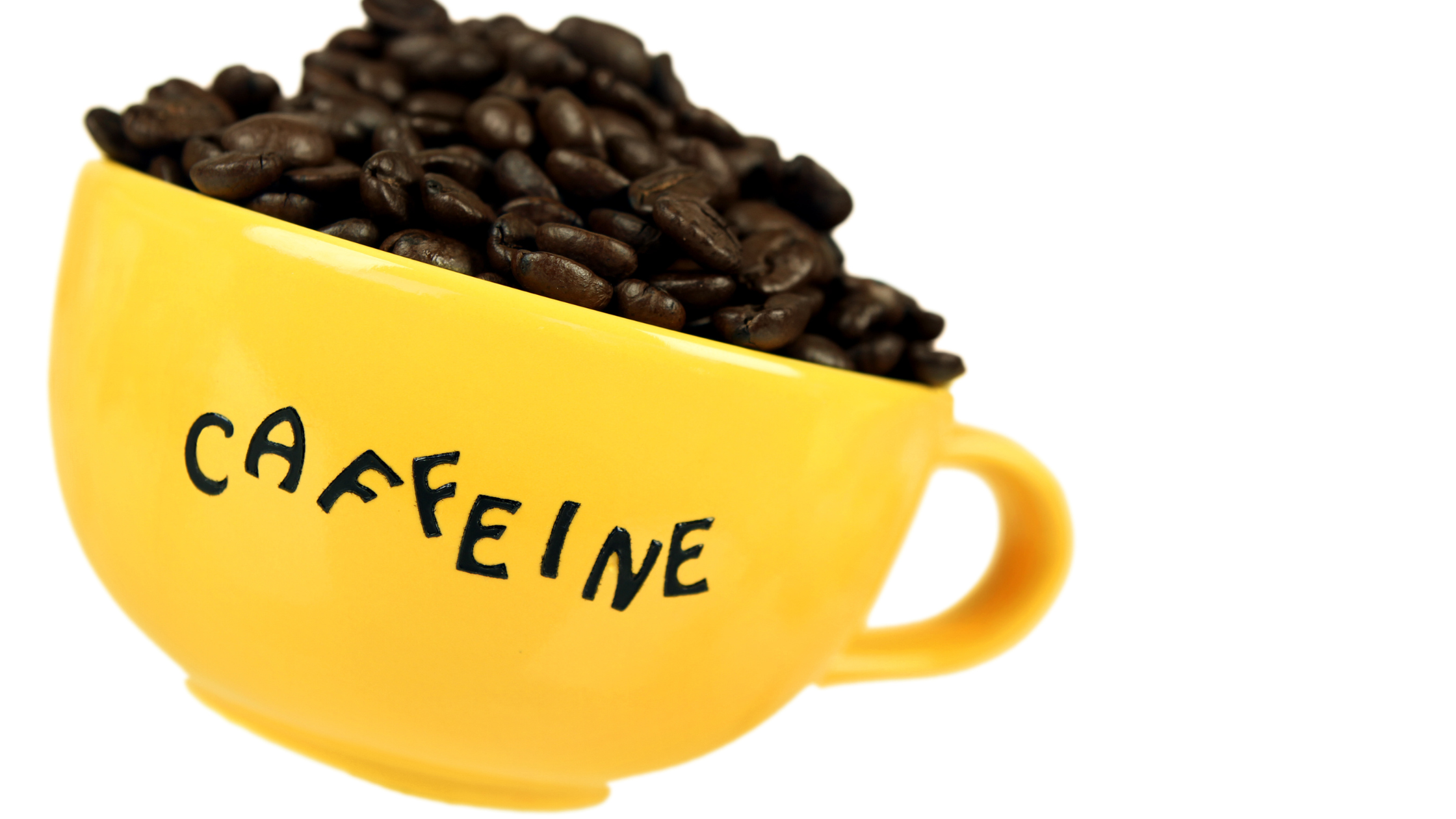 yellow mug reading "caffeine" full of coffee beans