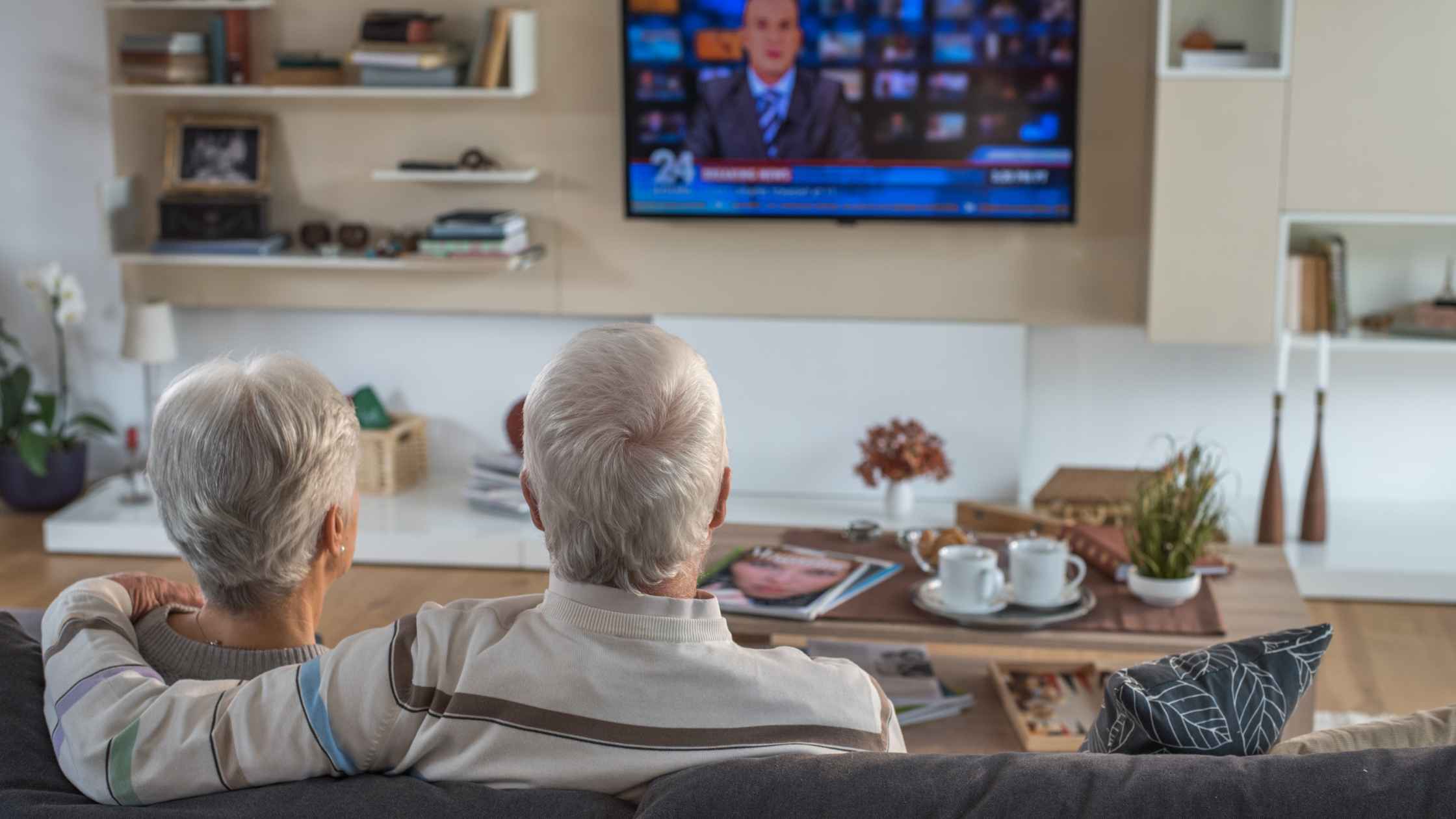 senior couple sitting on a couch watching TV