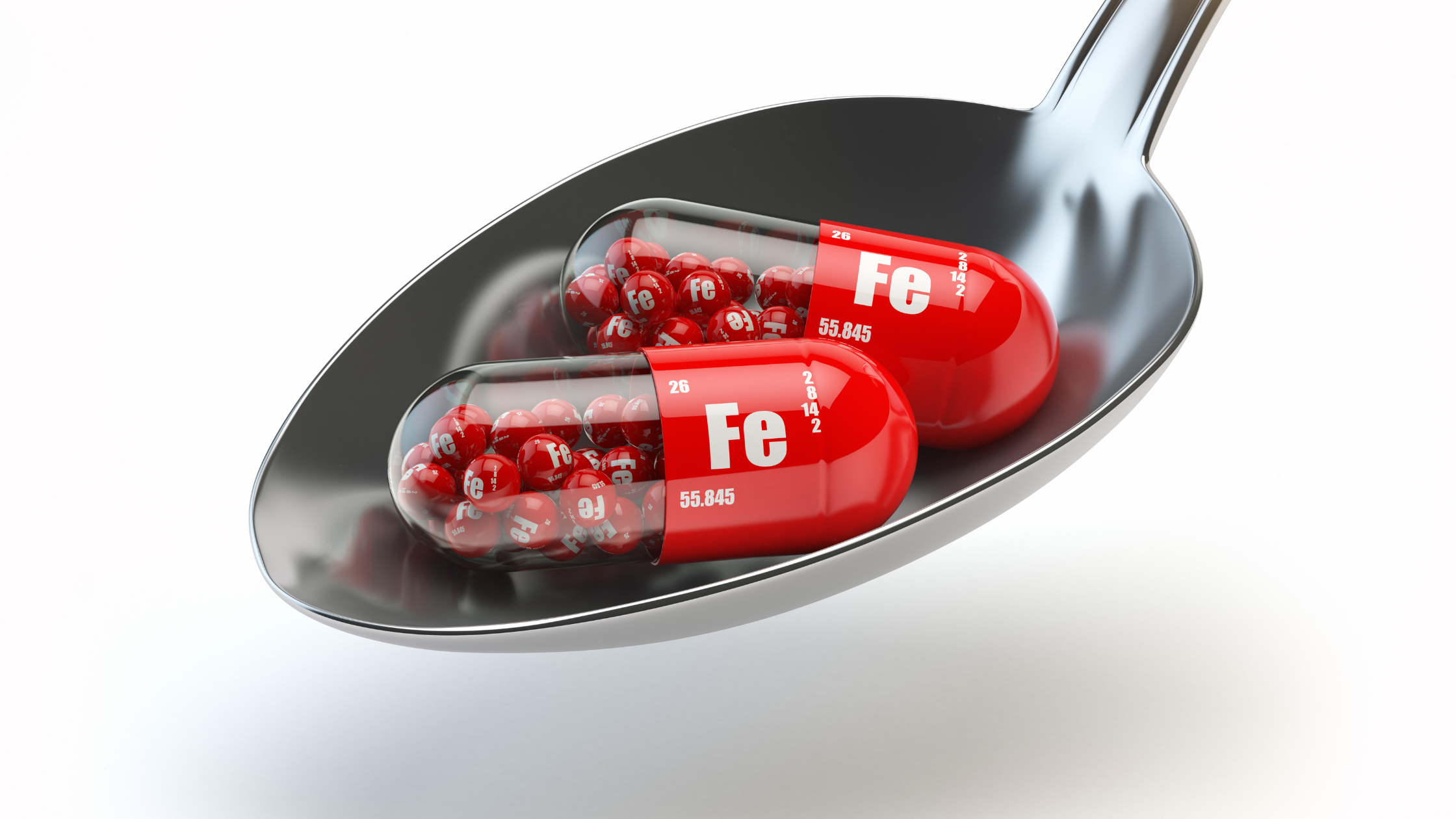 spoon full of capsules labeled "Fe" for iron