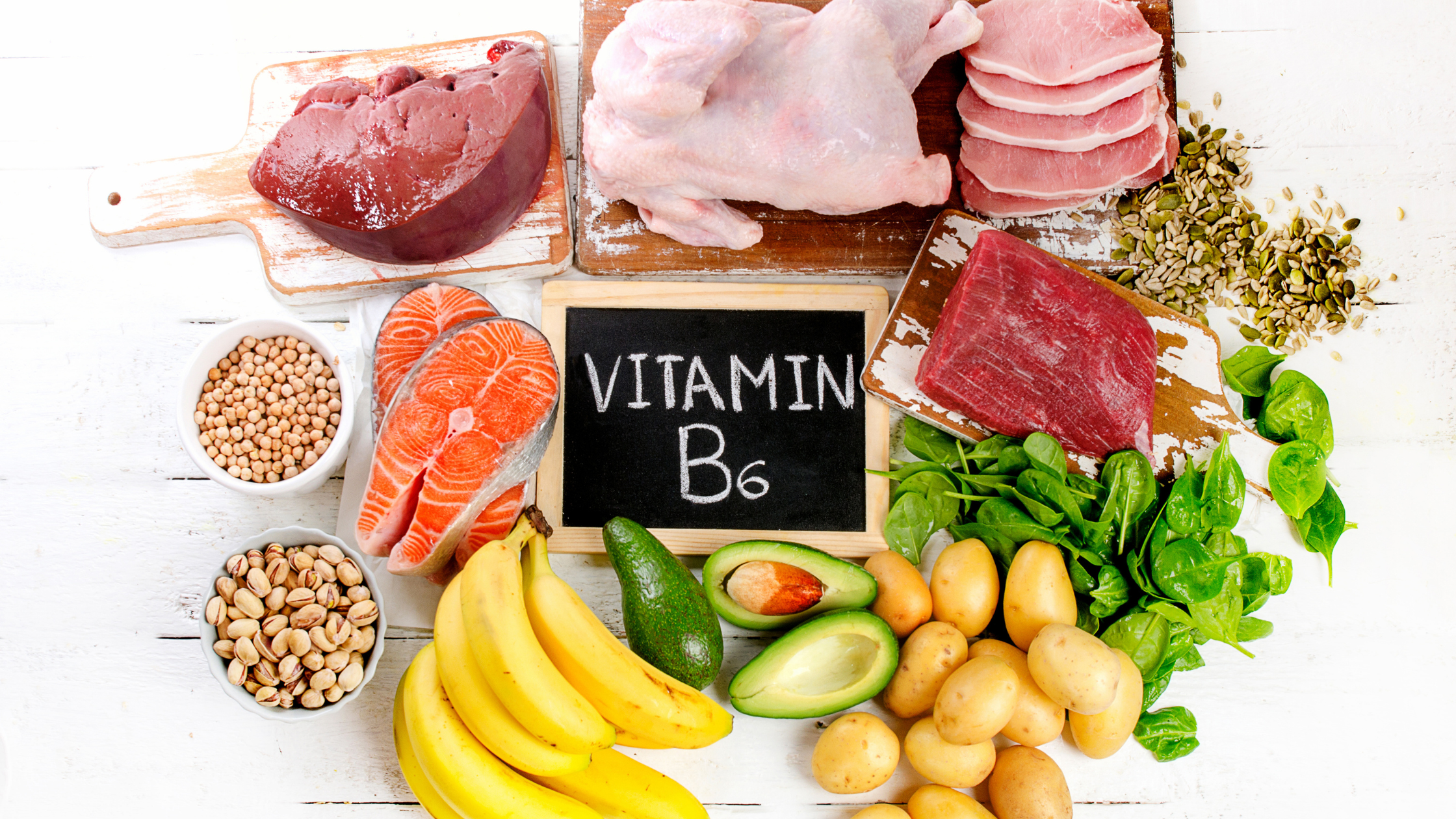 chalkboard reading "vitamin B6" surrounded by raw meats and fruits and veggies