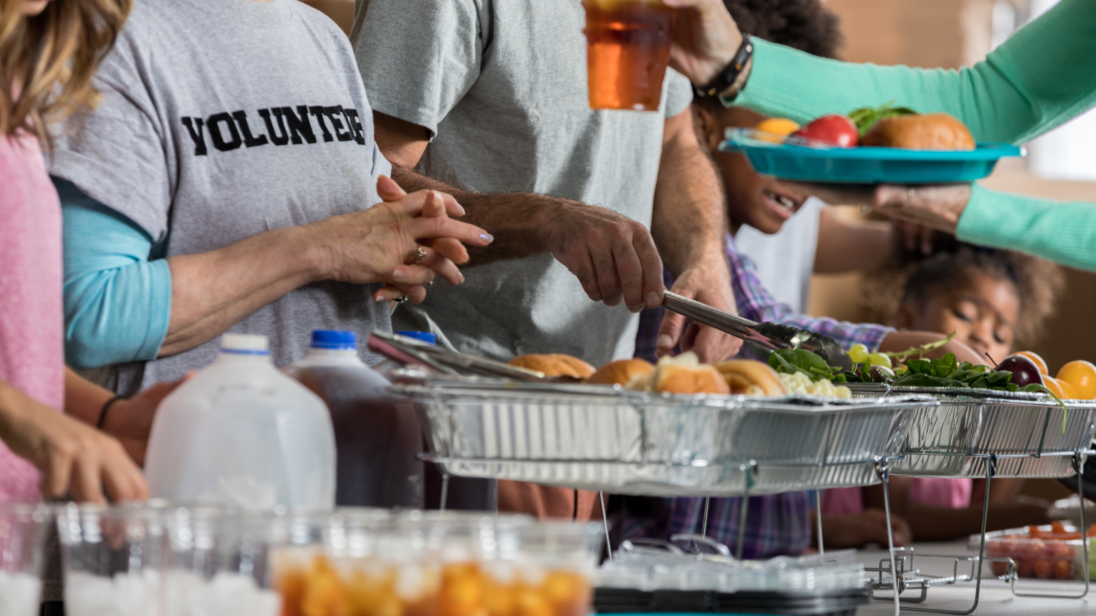 people in matching grey "volunteer" shirts serve food