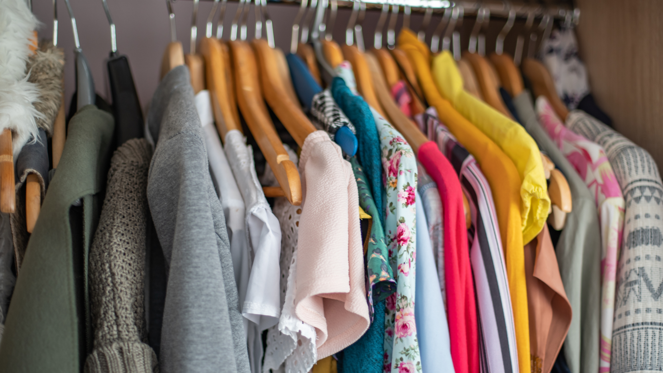 close up of a closet full of colorful clothes on hangars