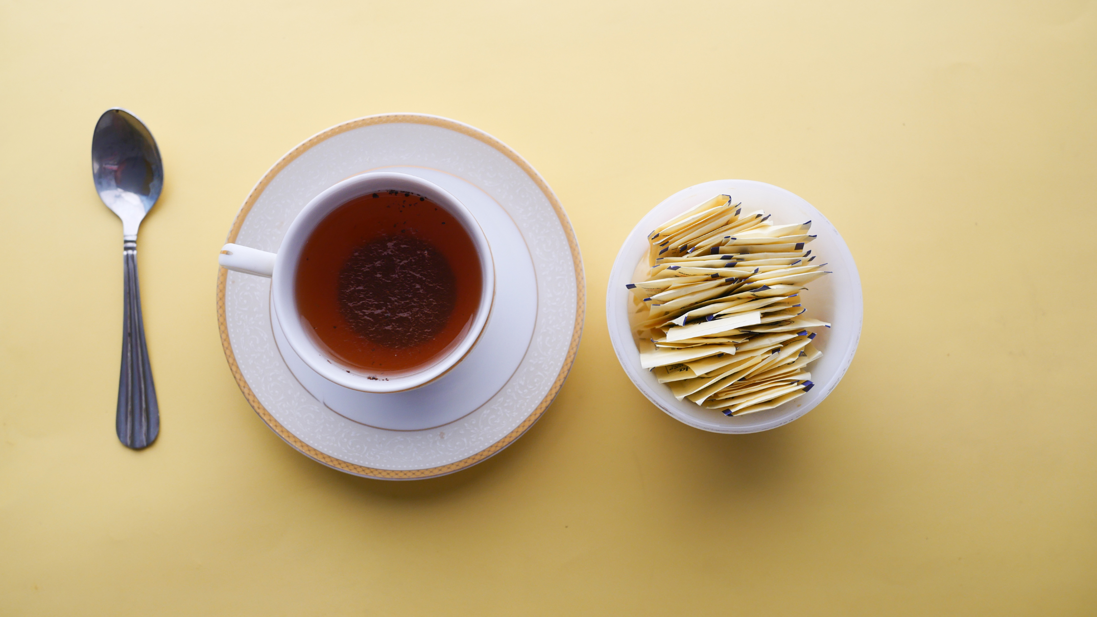cup of black tea beside a dish full of sweetener packets