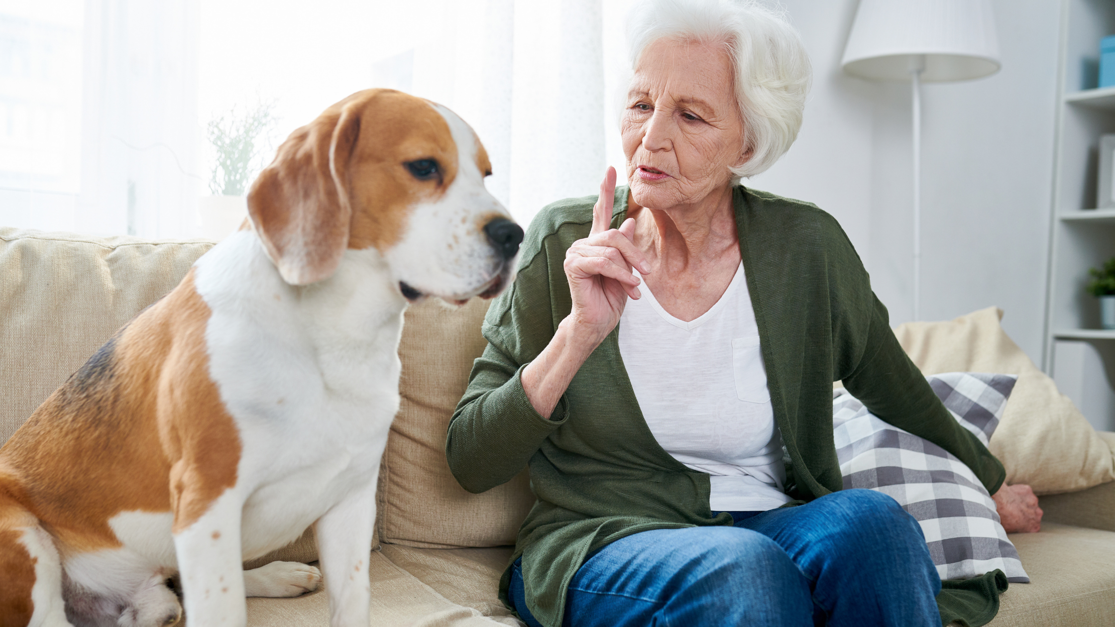 Senior woman holding up her finger and making a shushing face at her dog