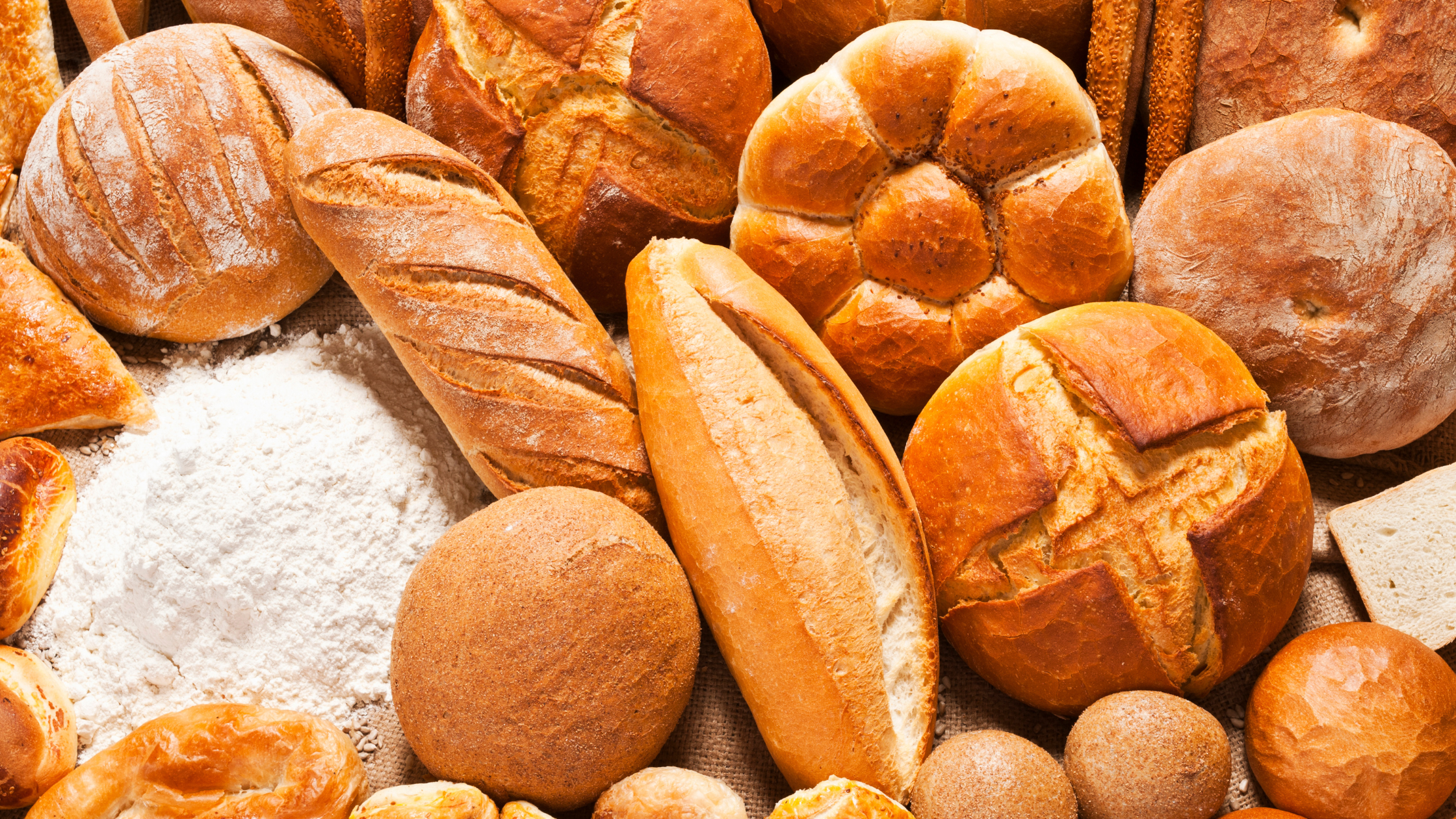 variety of fresh baked white breads and a pile of processed flour