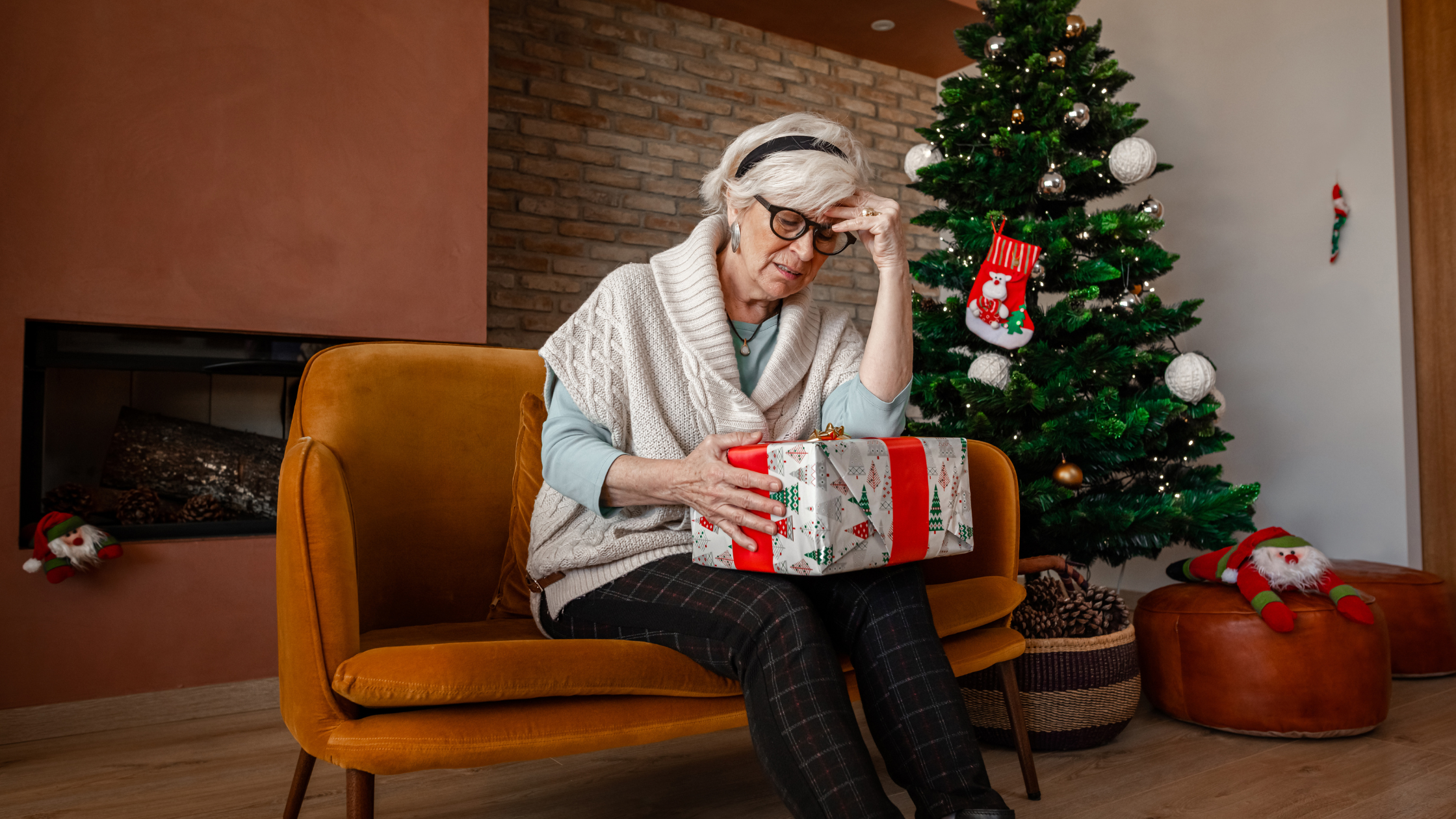 senior looks pensively at a wrapped present in their lap