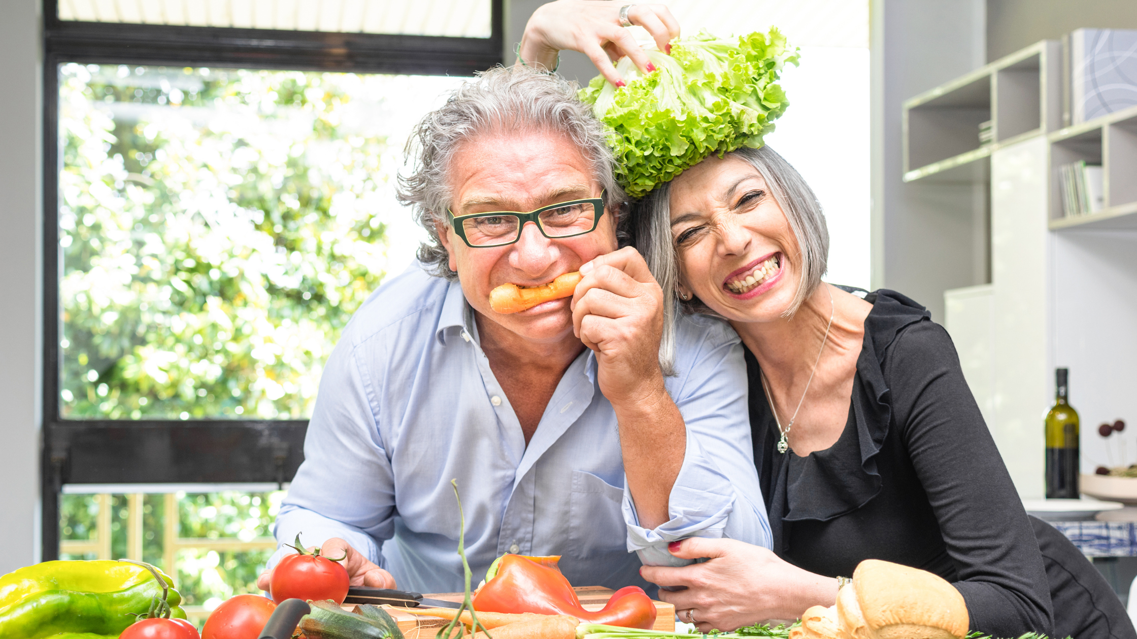 senior couple smiles and pose with fresh vegetables