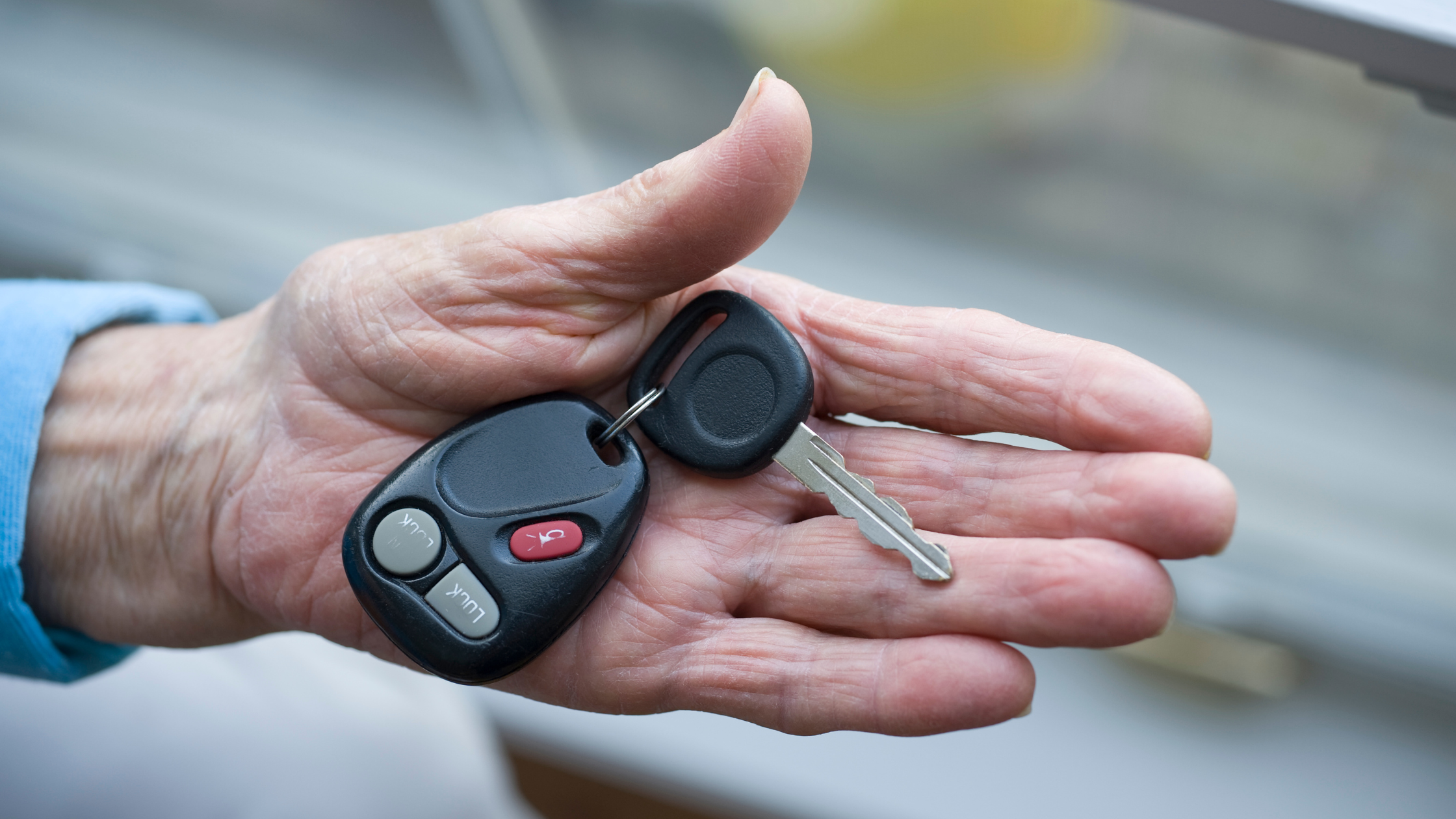 senior hand holds out a key fob