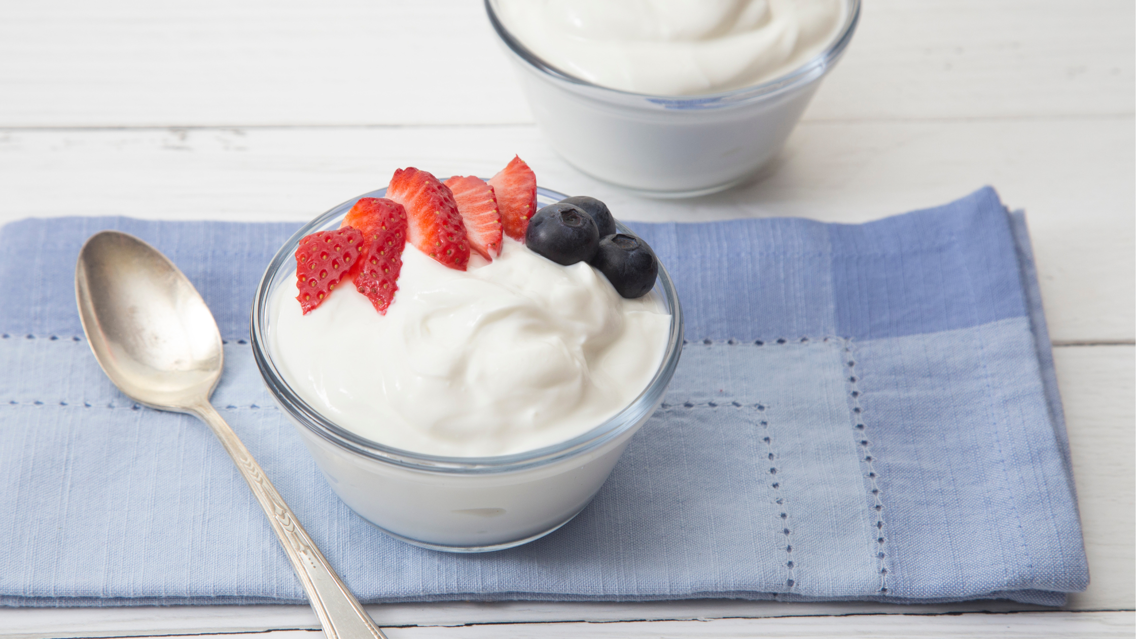 spoon sits beside a bowl of yogurt with fresh berries